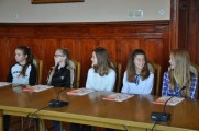 Grupa młodzieży siedzi przy stole konferencyjnym