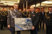 Wojciech Mendelak z obrazem przedstawiającym samolot F-16. 