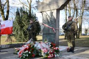 Żołnierz pełni wartę przy pomniku, przed którym leżą kwiaty