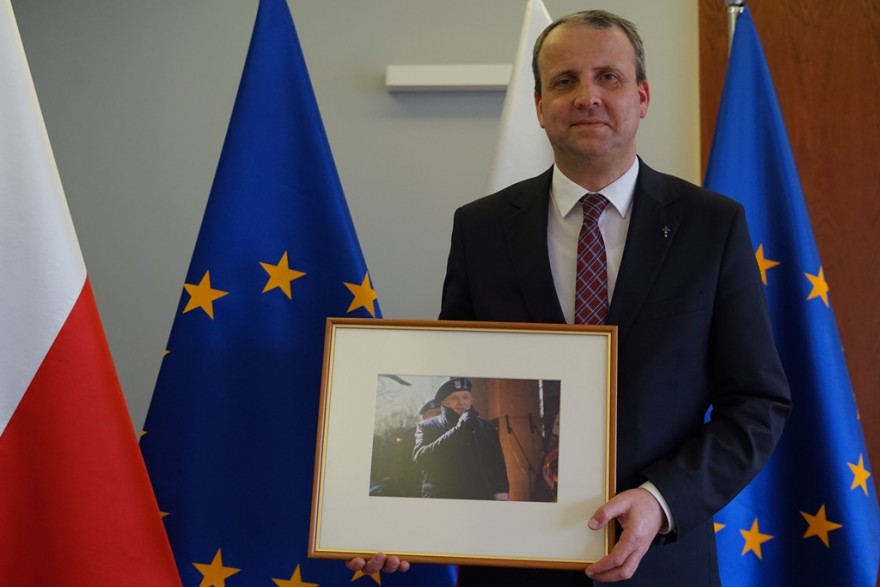 Wojewoda trzyma w ręku pamiątkowe zdjęcie z dedykacją dla kombatanta Jana Górskiego